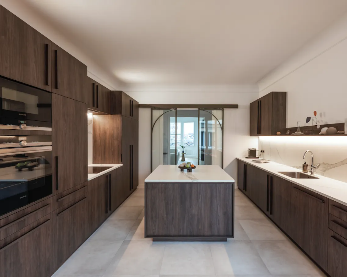 Cuisine moderne avec armoires en bois foncé, comptoirs blancs et îlot central.