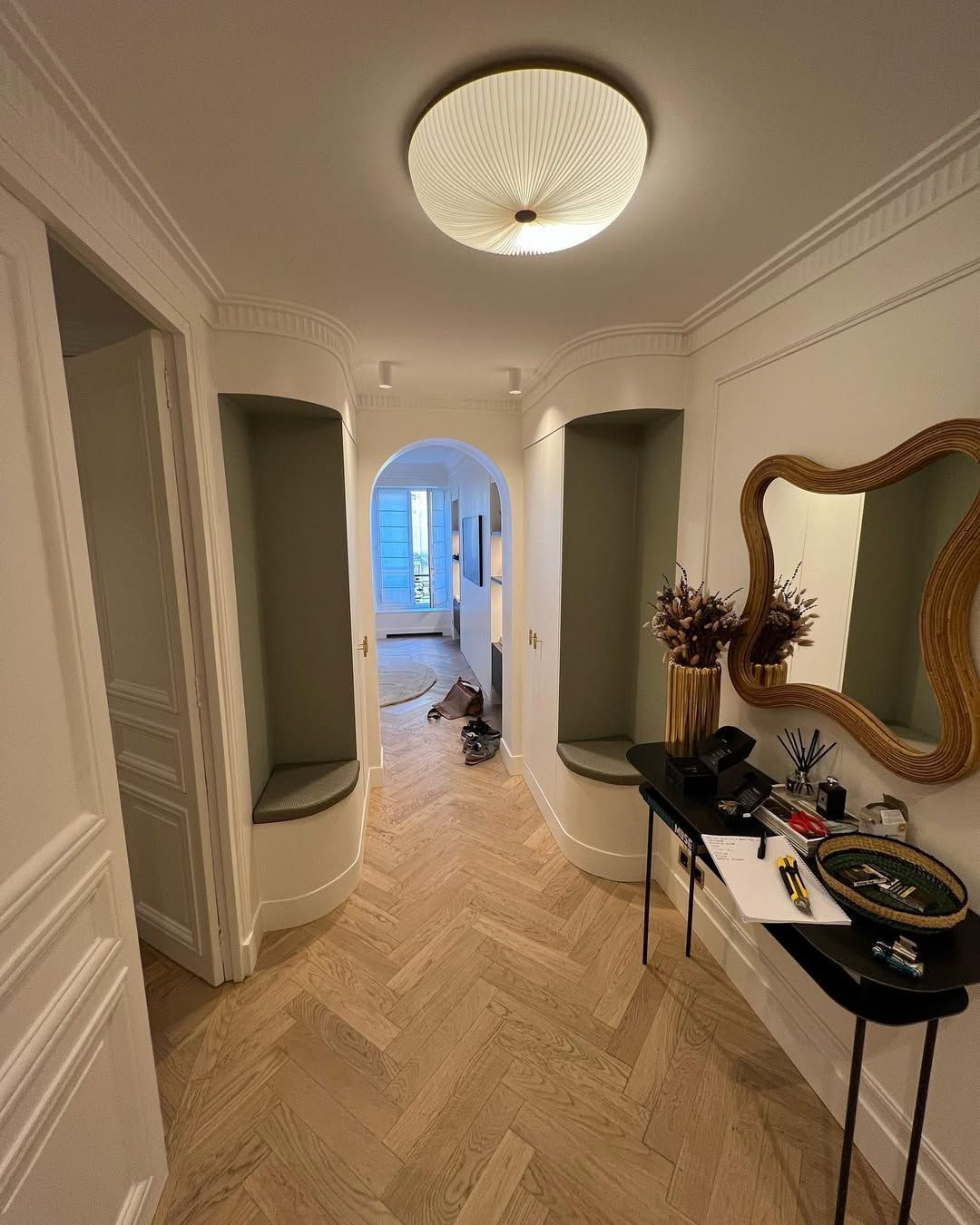 Couloir avec parquet à chevrons, bancs intégrés et miroir.