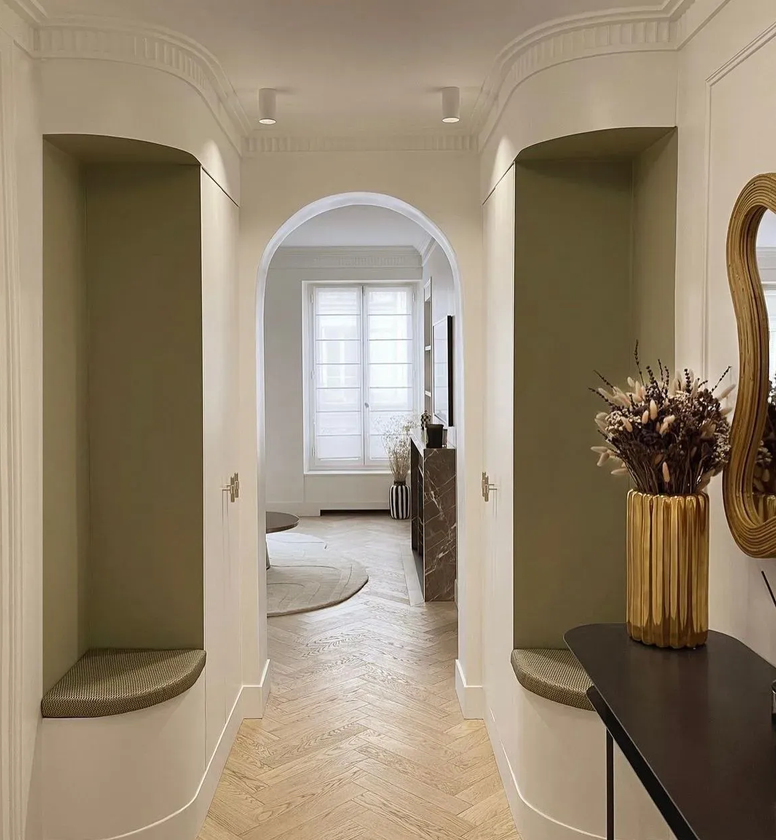 Couloir moderne, parquet et console avec miroir et fleurs.