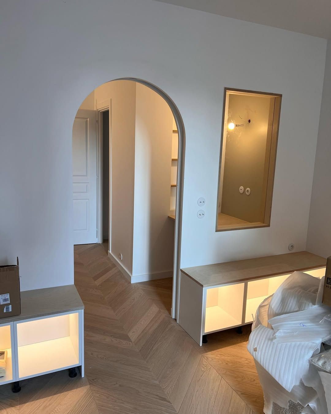 Intérieur avec porte cintrée, parquet clair, placard intégré, miroir mural et éclairage encastré.