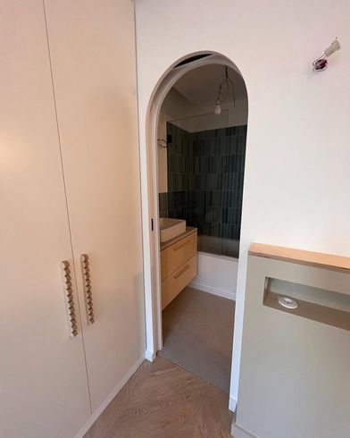 Porte de salle de bains donnant sur le meuble vasque et la douche.