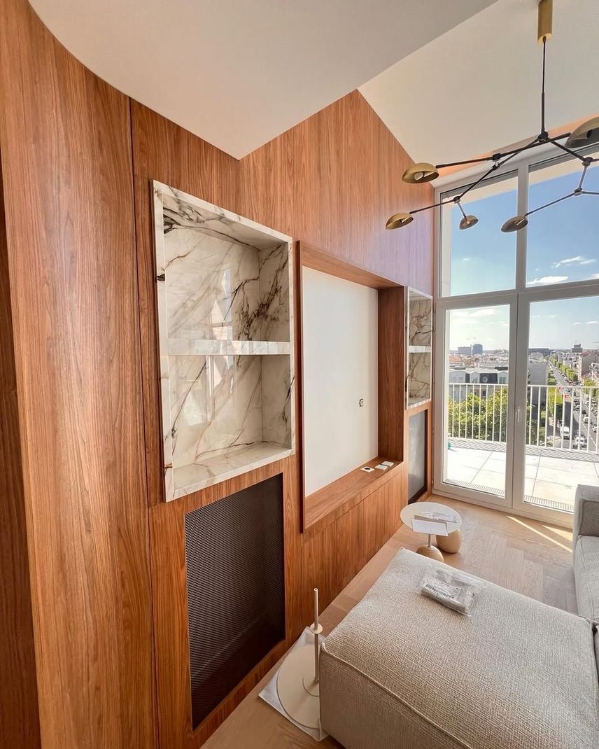 Mur avec une étagère en marbre, un panneau blanc et une grande fenêtre donnant sur un paysage urbain.