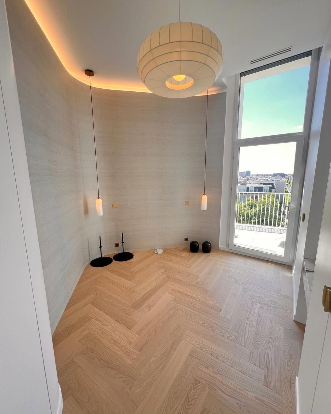 Chambre avec parquet et éclairage moderne. Grande fenêtre donnant sur un balcon.