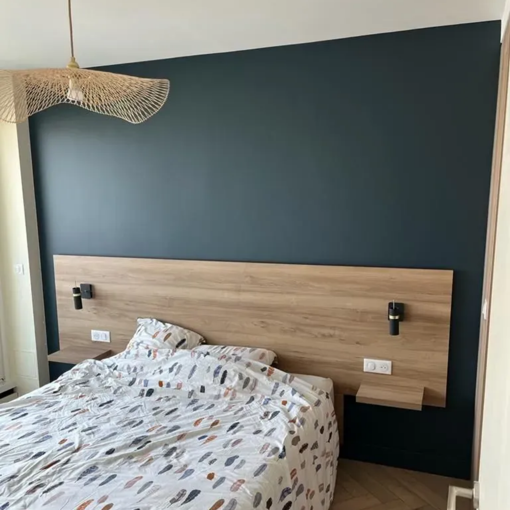 Chambre avec un mur d'accent turquoise, une tête de lit en bois avec lampes de chevet et étagères et une literie à motifs.