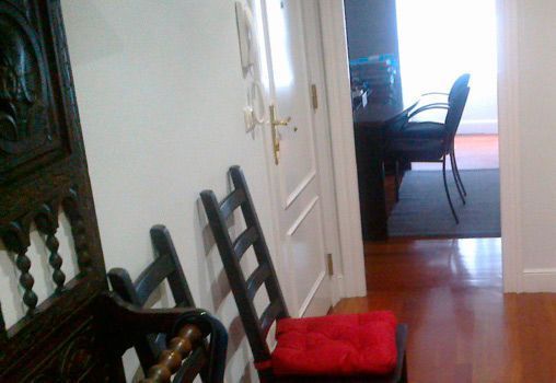 Un pasillo con dos sillas y un cojín rojo.