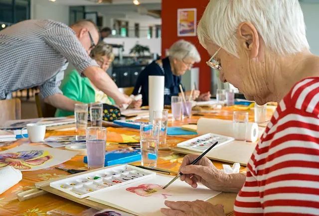 Un grupo de personas están sentadas alrededor de una mesa pintando.