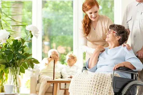 Una mujer está de pie junto a una anciana en silla de ruedas.