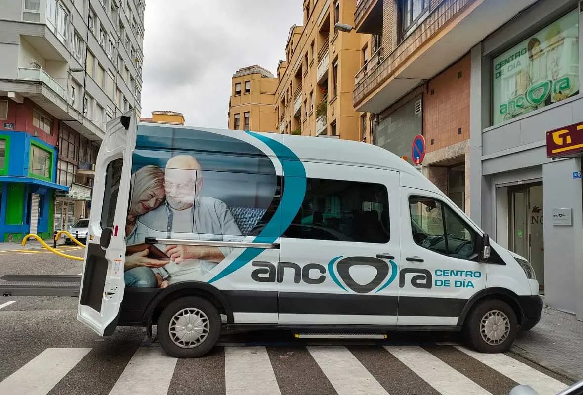Una camioneta blanca está estacionada al costado de la carretera frente a un edificio.