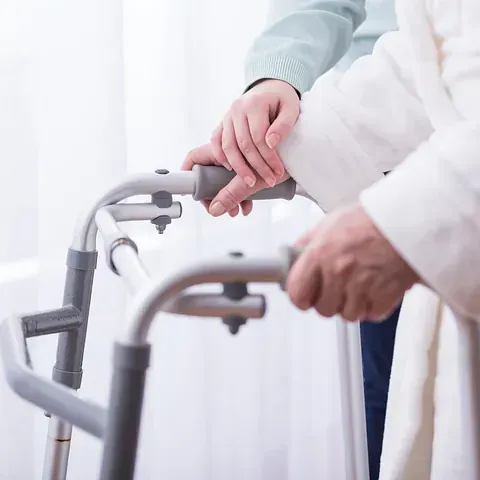Una persona está ayudando a otra persona a usar un andador.