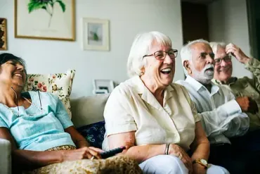 Un grupo de personas mayores están sentadas en un sofá riendo.