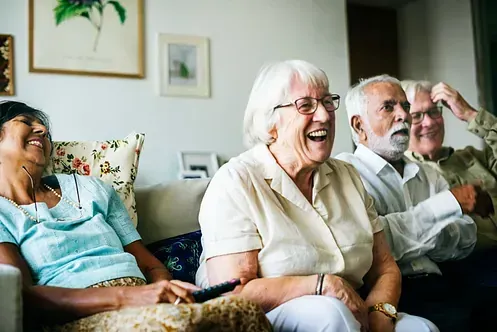 Un grupo de personas mayores están sentadas en un sofá riendo.