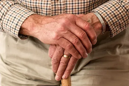 Un hombre con un anillo en su dedo sostiene un bastón.