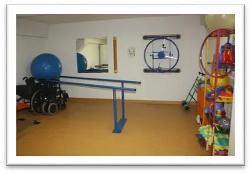 Una imagen de un gimnasio con una pelota azul y una silla de ruedas.