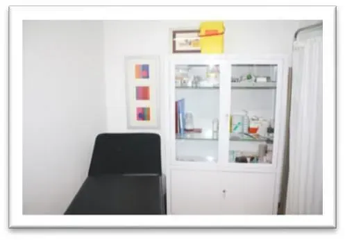 Un consultorio médico con una cama y un gabinete.
