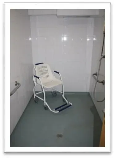 Una silla de ruedas está sentada en un baño al lado de una ducha.