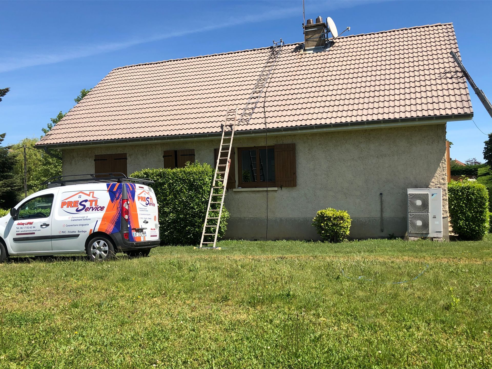 Camion Prestiservice dans un jardin devant une maison sous un ciel bleu