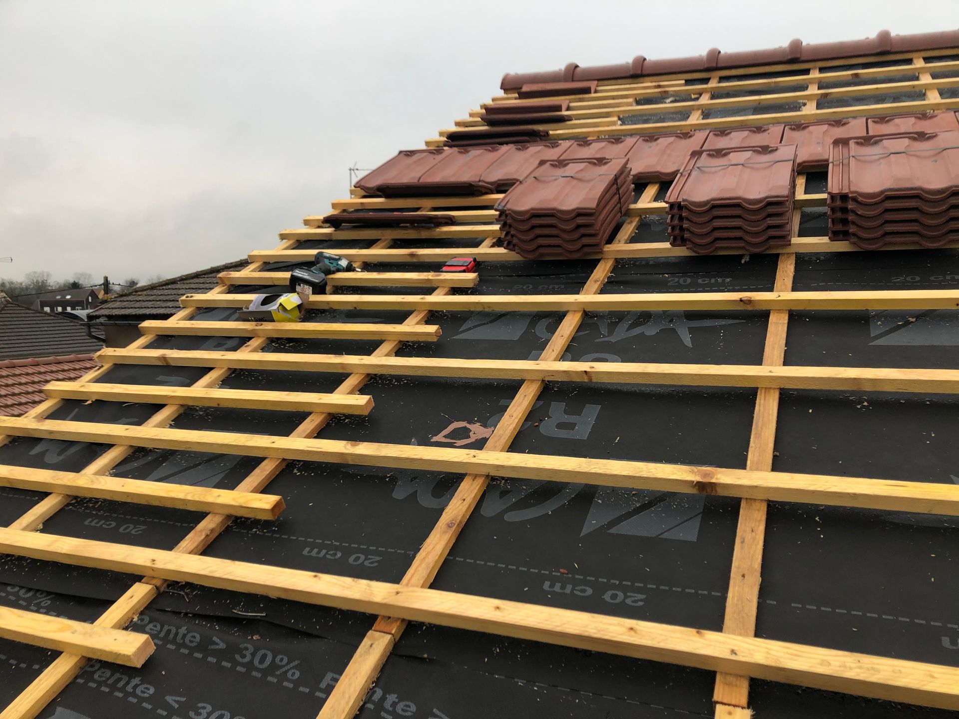 Chantier de couverture avec piles de tuiles sous un ciel gris