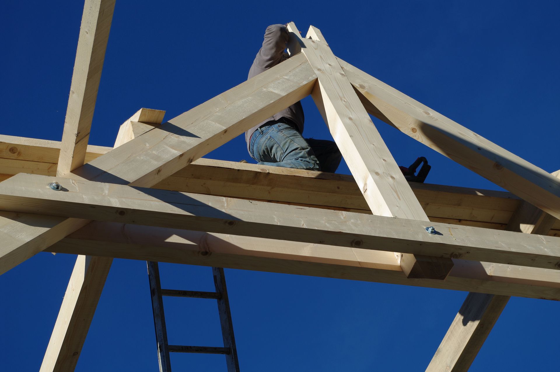 Vue en contre-plongée d'un charpentier sur une charpente en chantier