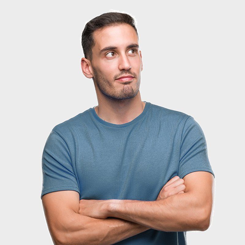 Un hombre con una camisa azul está de pie con los brazos cruzados y mirando hacia arriba.