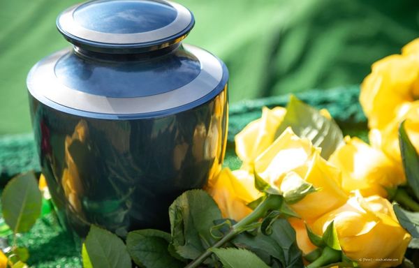 Blaue Urne, umgeben von gelben Rosen und grünen Blättern