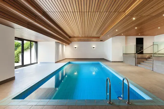 Una piscina cubierta con techo de madera y escaleras.