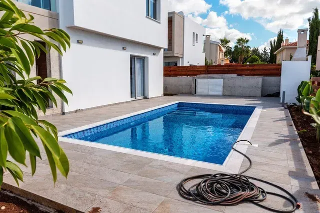 Una gran piscina está en el patio trasero de una casa.