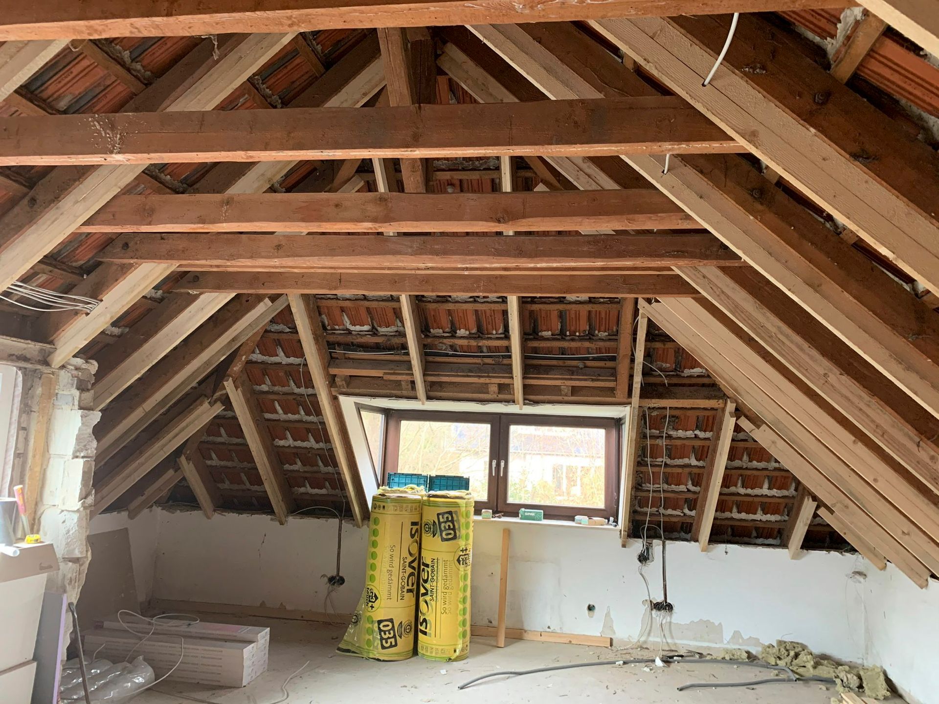 ein Dachboden mit Holzbalken und einem Fenster