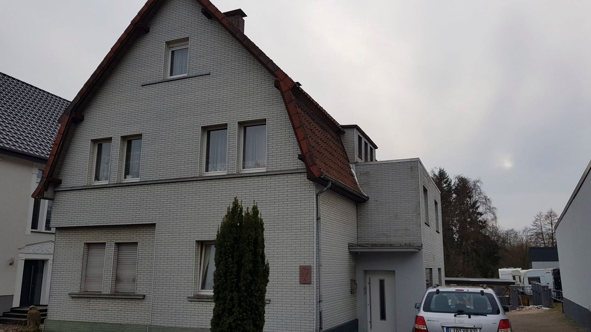 ein weißes Haus mit einem davor geparkten Auto.