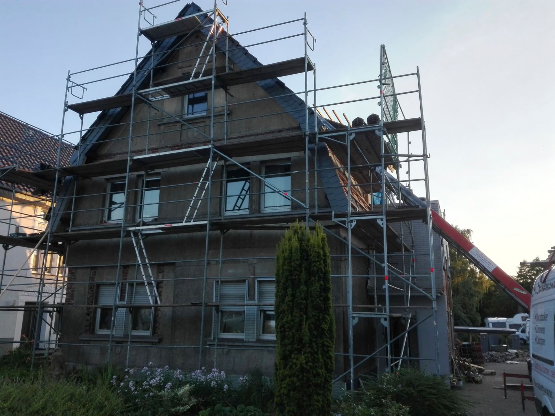 ein Gebäude mit einem Gerüst drumherum und einem Kran im Hintergrund