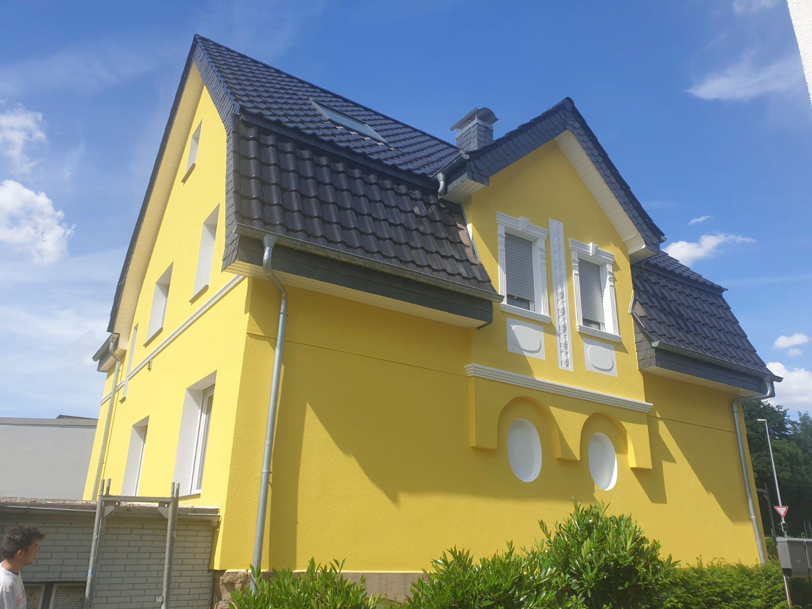 ein gelbes Haus mit schwarzem Dach und weißen Fenstern