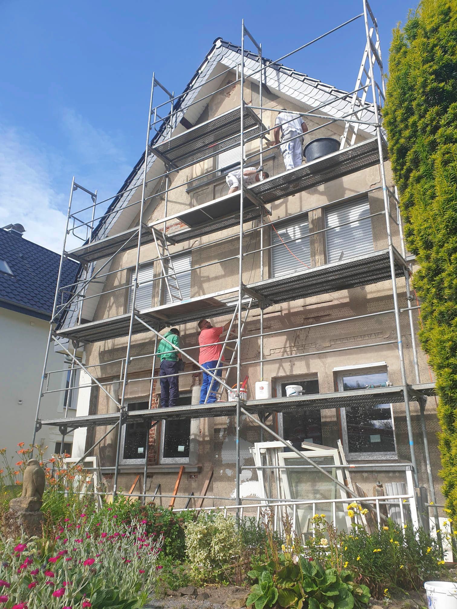 Ein Haus wird mit einem Gerüst darum gestrichen.