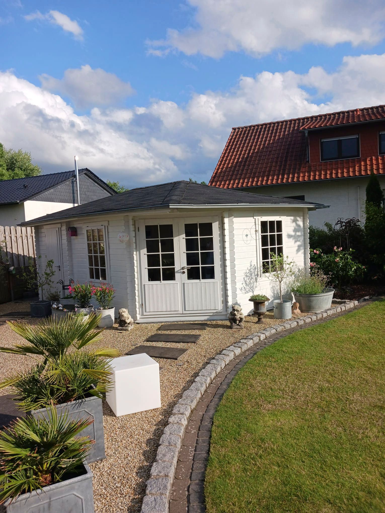 Ein kleines weißes Haus steht inmitten eines üppig grünen Gartens.