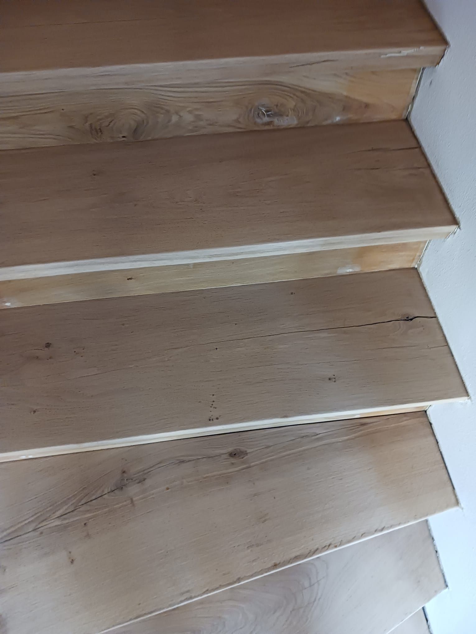 Eine Nahaufnahme einer Holztreppe mit einer weißen Wand im Hintergrund.
