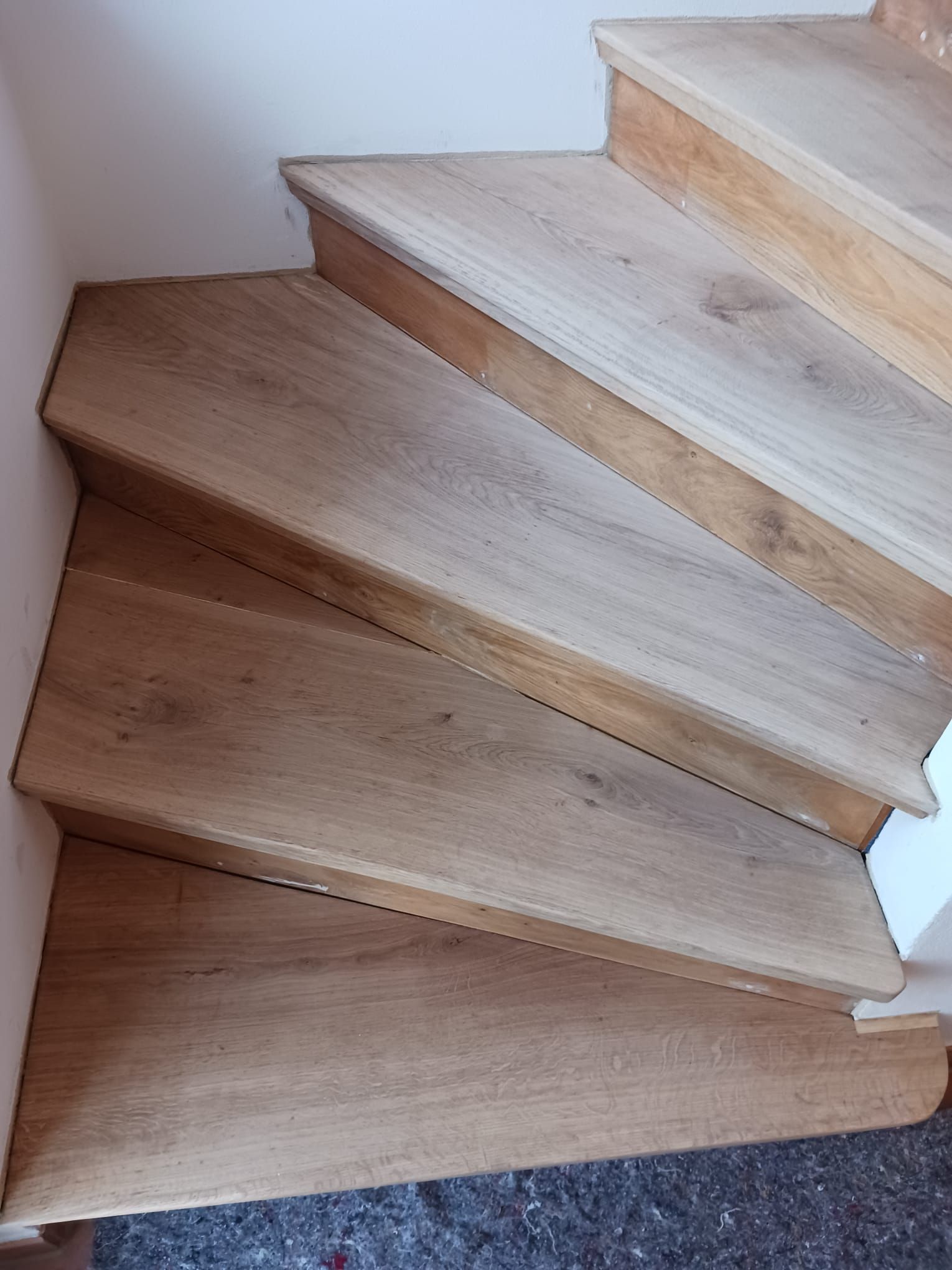 Eine Nahaufnahme einer Holztreppe mit einer weißen Wand im Hintergrund.