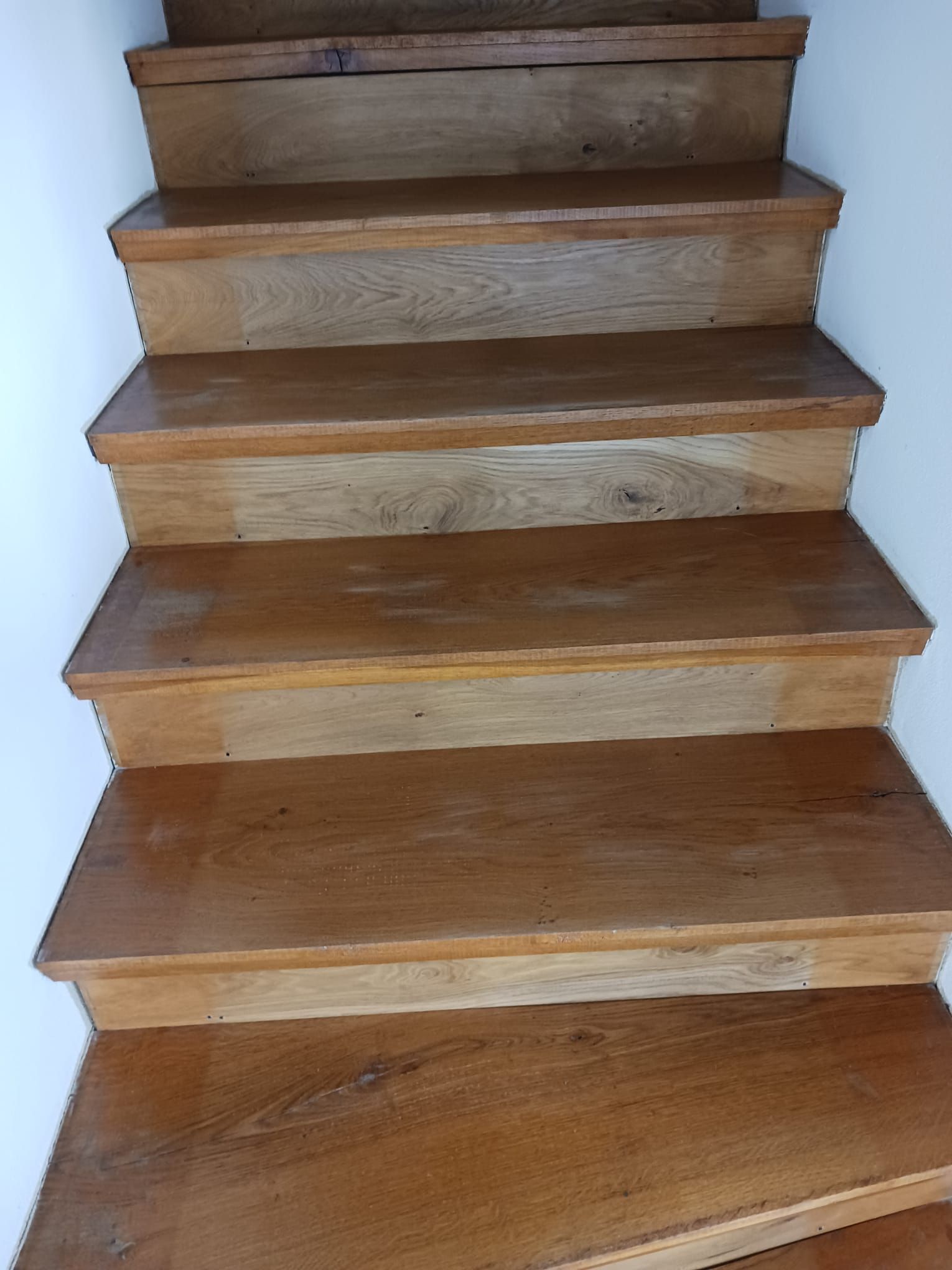 eine Nahaufnahme einer Holztreppe mit einer weißen Wand im Hintergrund.