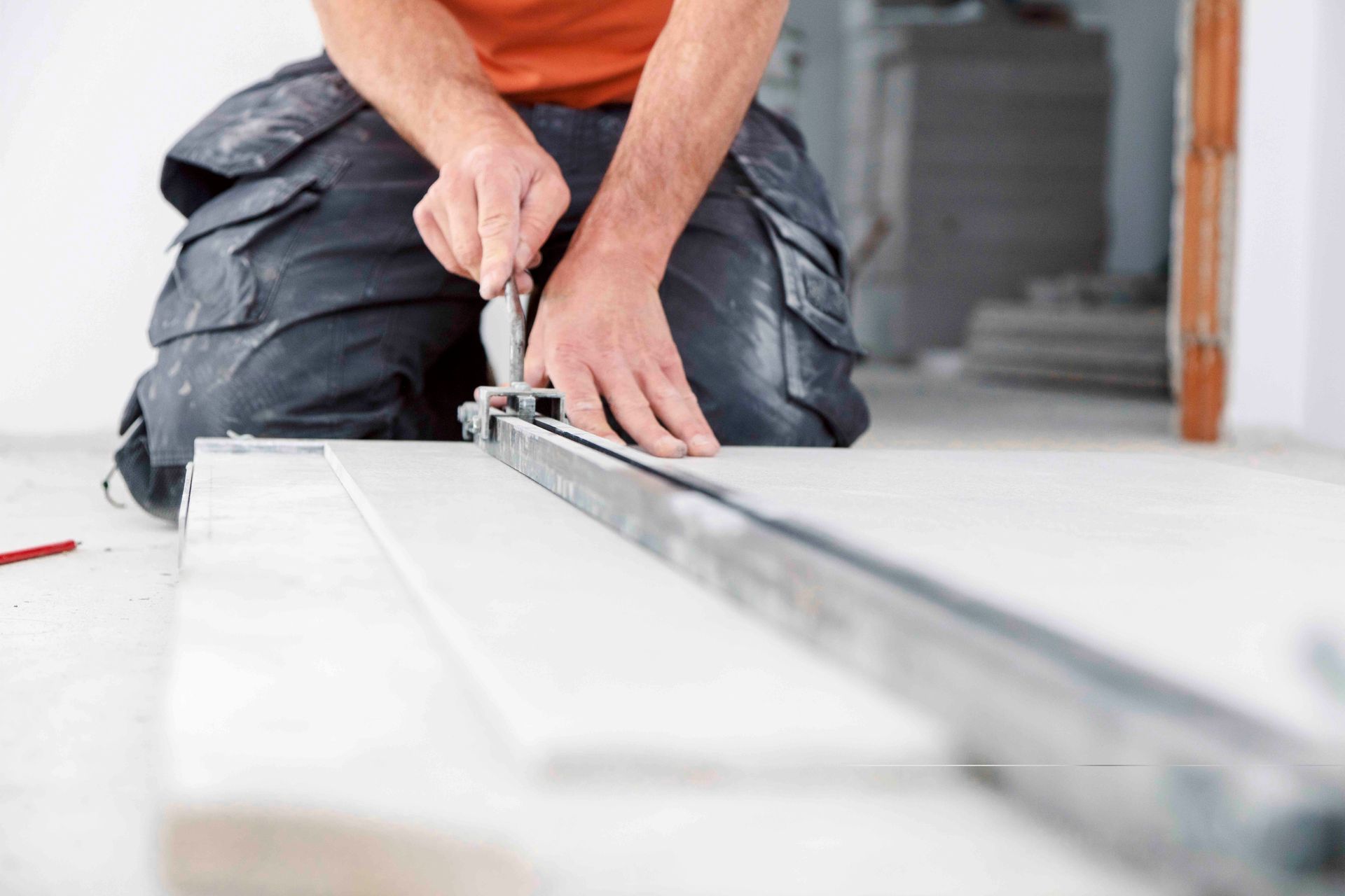 Ein Mann kniet mit einem Maßband auf dem Boden.