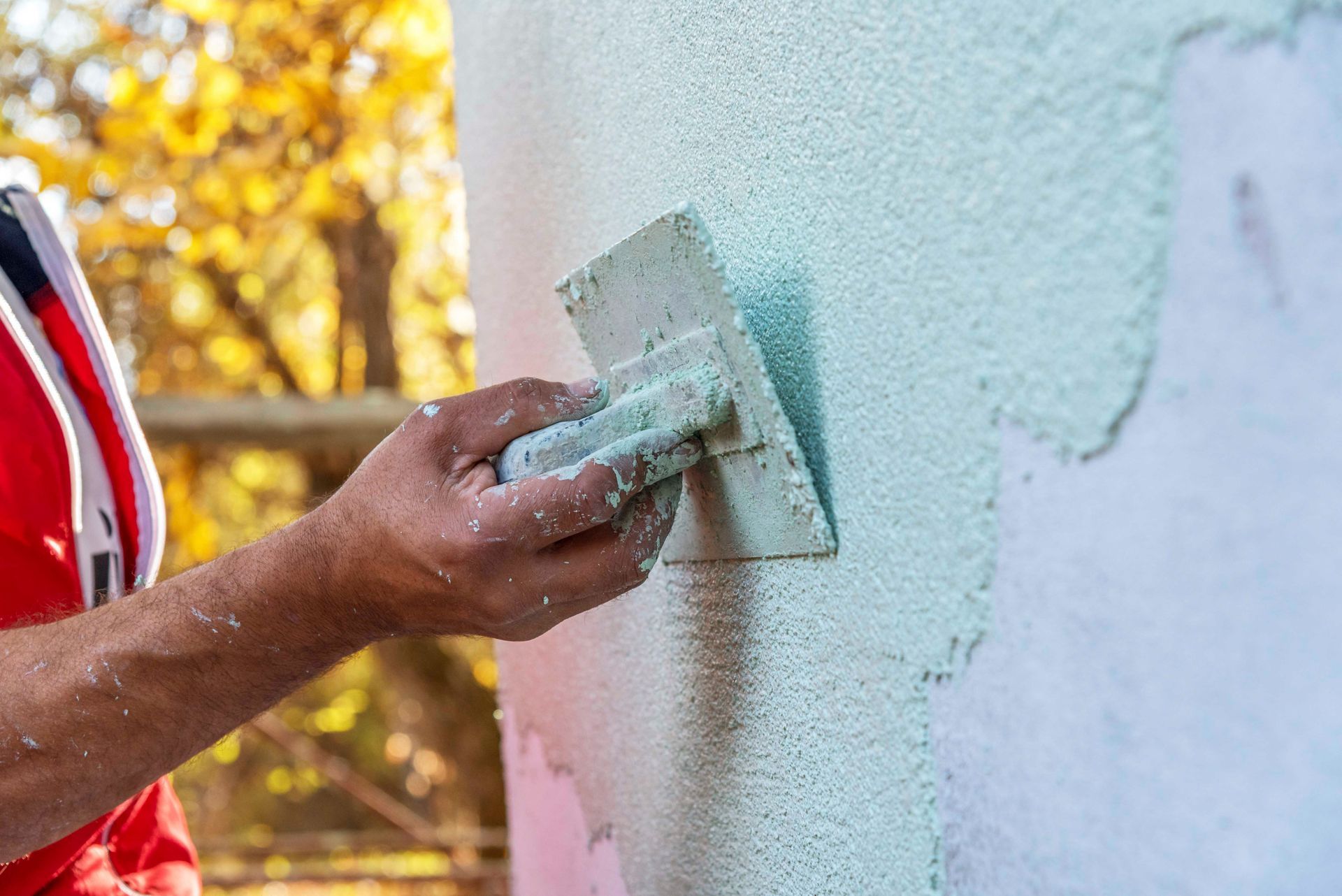 Ein Mann verputzt eine Wand mit einer Kelle.