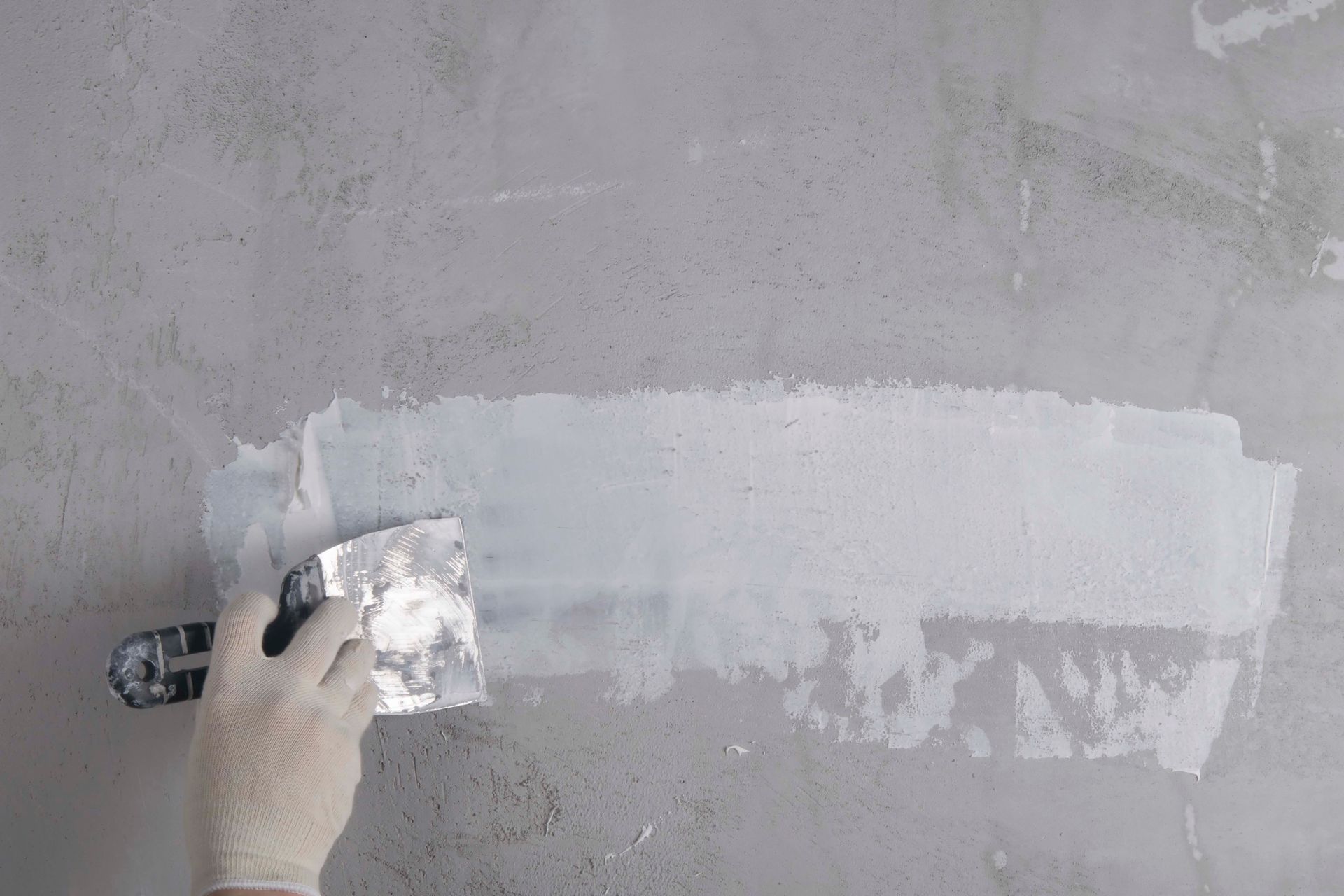 Eine Person verputzt eine Wand mit einem Spachtel.