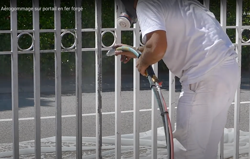 Technicien habillé en blanc en train de décaper un portail