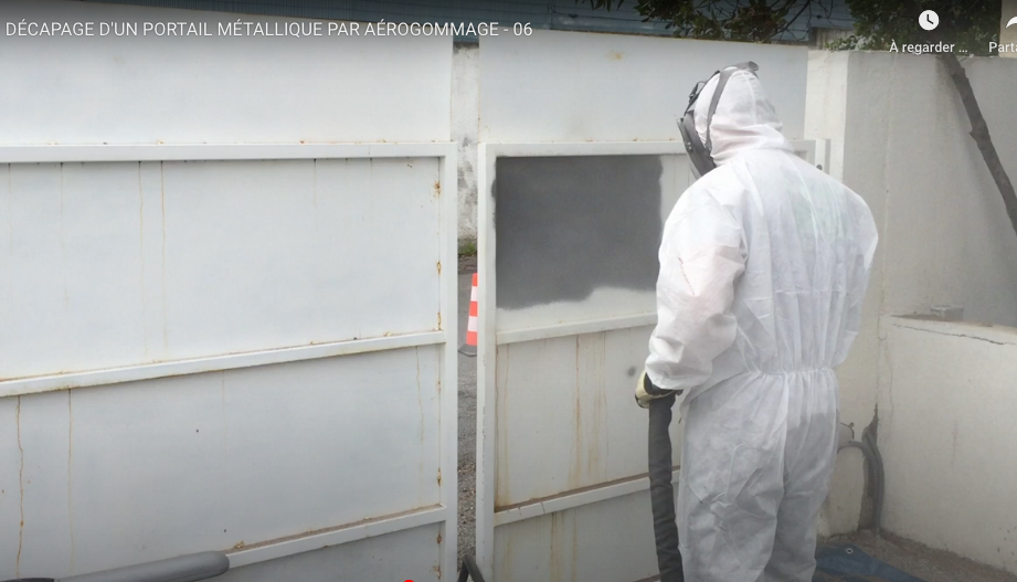 Technicien protégé devant un grand portail blanc