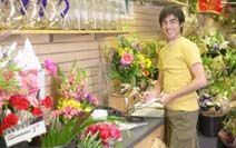 Persona arreglando flores en una colorida floristería.