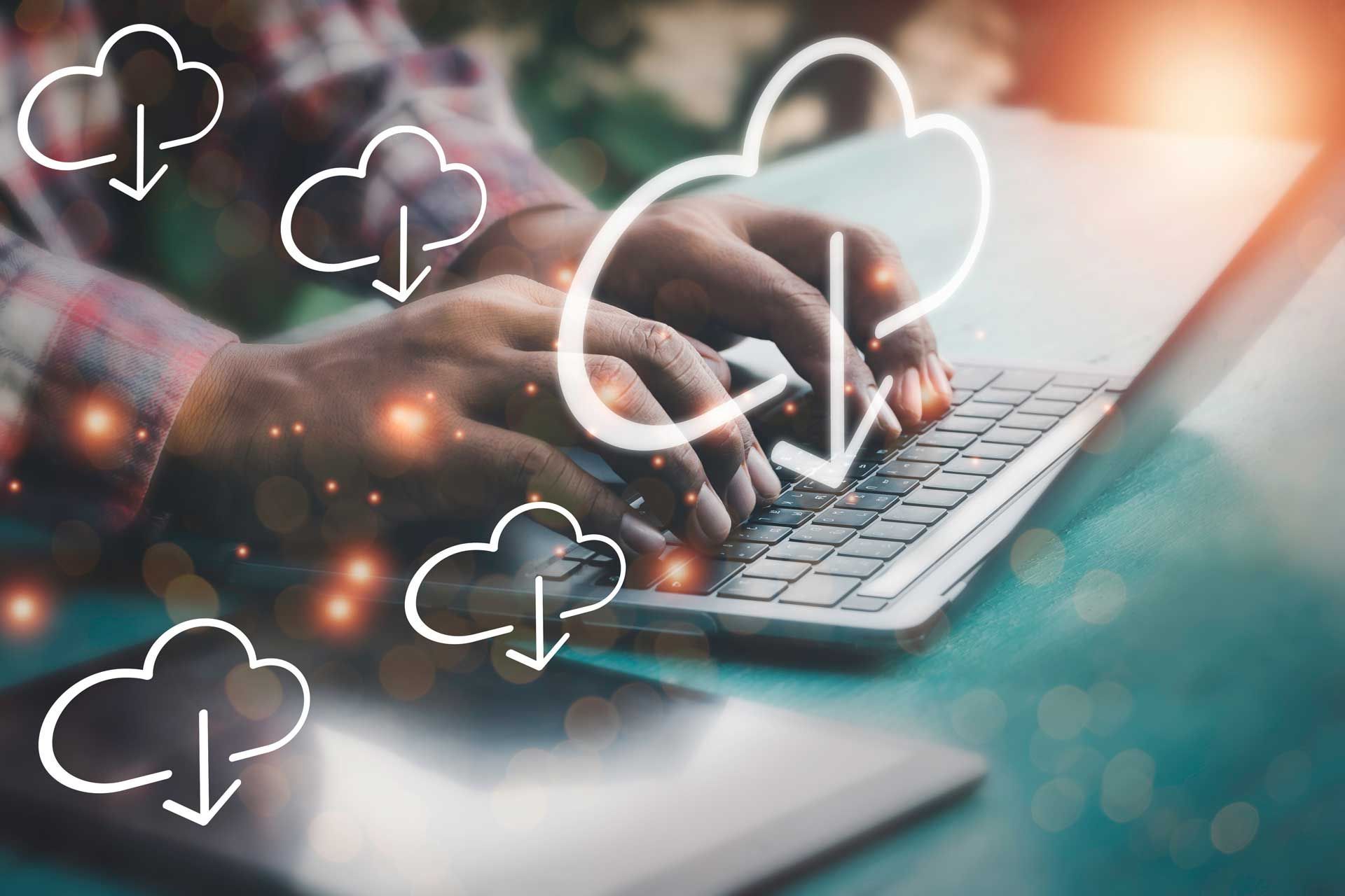 Eine Person tippt auf einem Laptop, über dem Cloud-Download-Symbole eingeblendet sind, was auf eine Datenübertragung in der Cloud hindeutet.