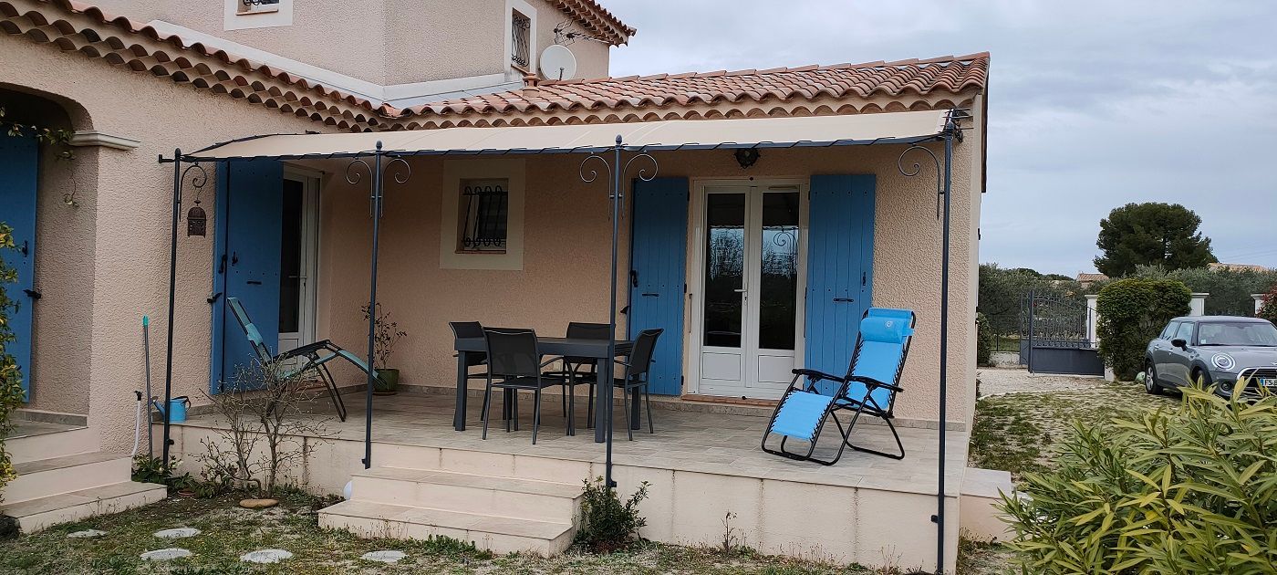 Entoilage de pergola d'une maison avec des volets bleus