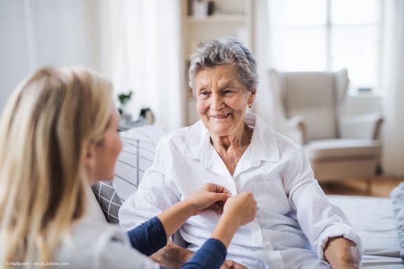 Pflegerin hält die Hand auf die Hand einer Seniorin