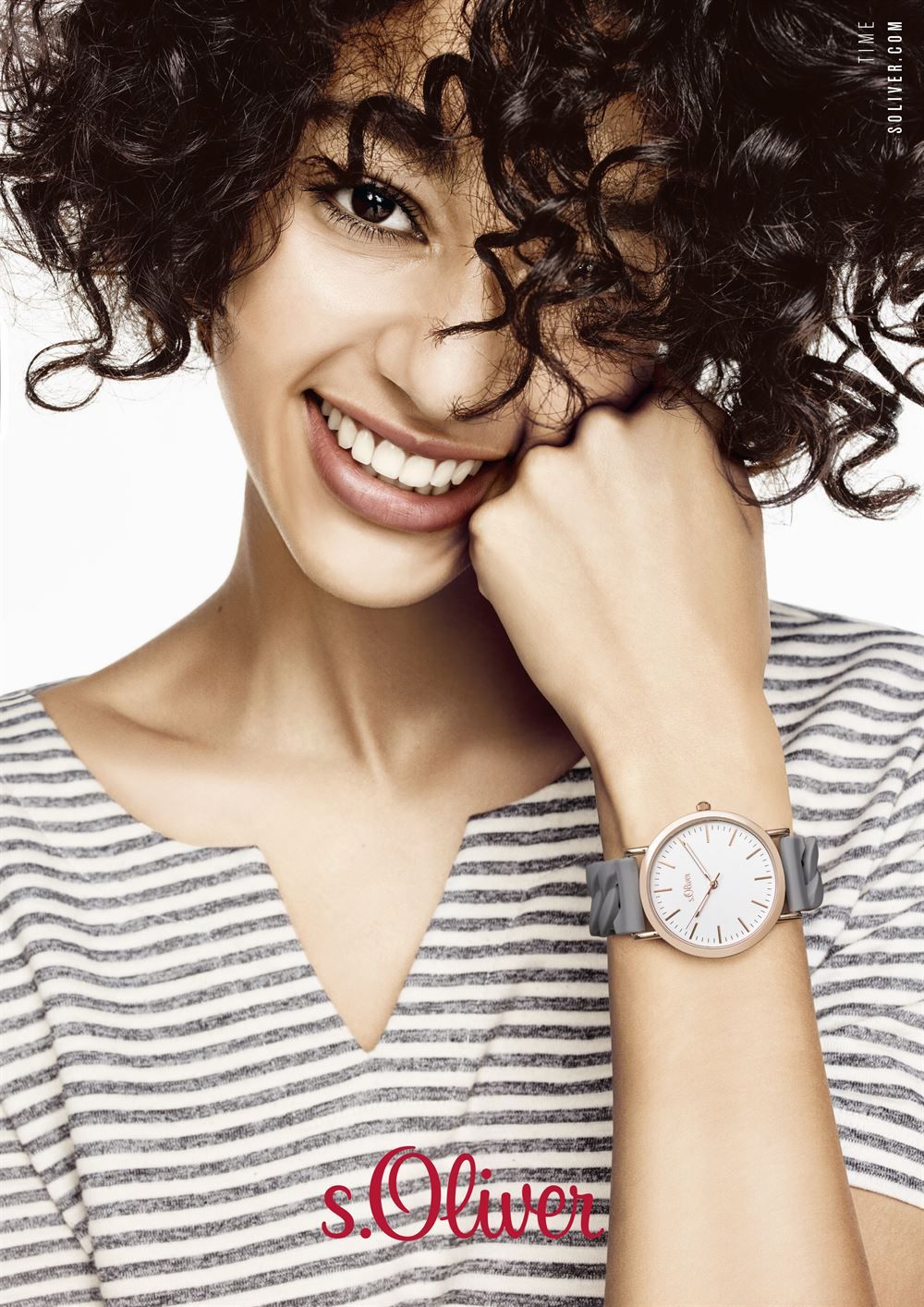 Eine Frau mit gestreiftem Hemd und Uhr lächelt