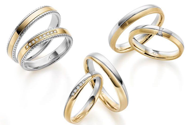 Ein paar Eheringe liegen nebeneinander auf einer weißen Fläche.