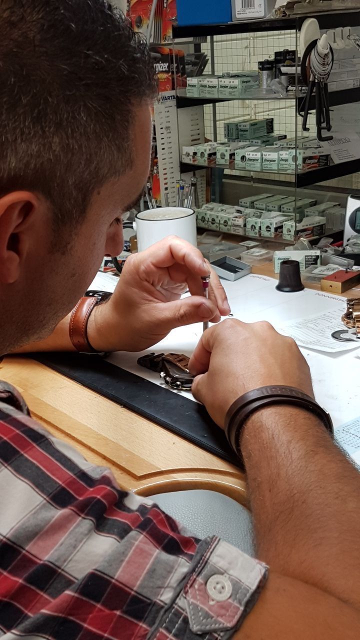 Ein Mann im karierten Hemd arbeitet an einer Uhr