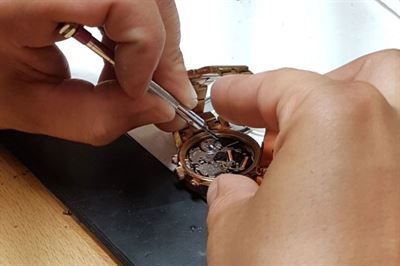 Eine Person repariert eine Uhr mit einem Schraubenzieher.