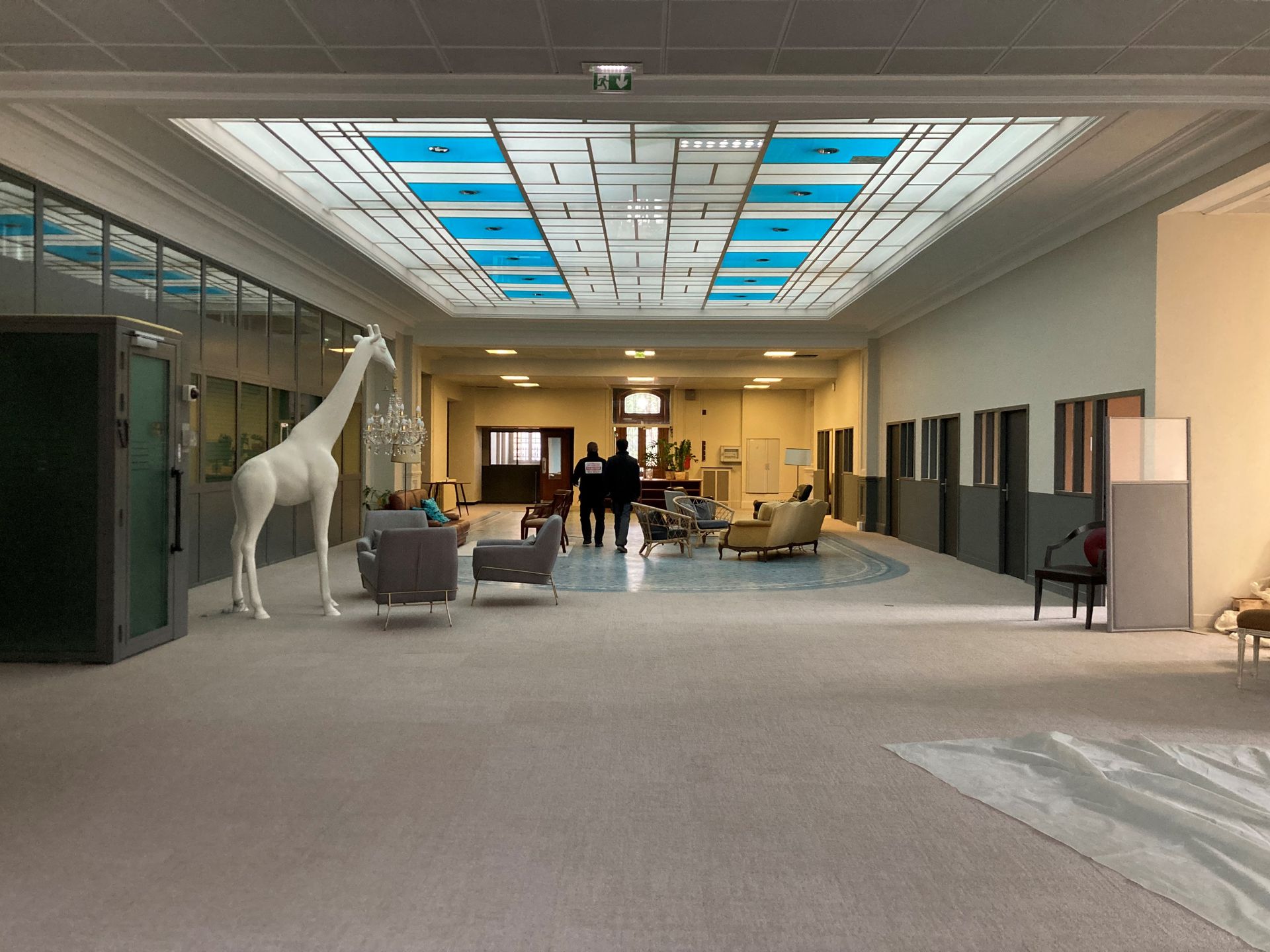 Intérieur d'un hall avec des fauteuils et une girafe décorative.
