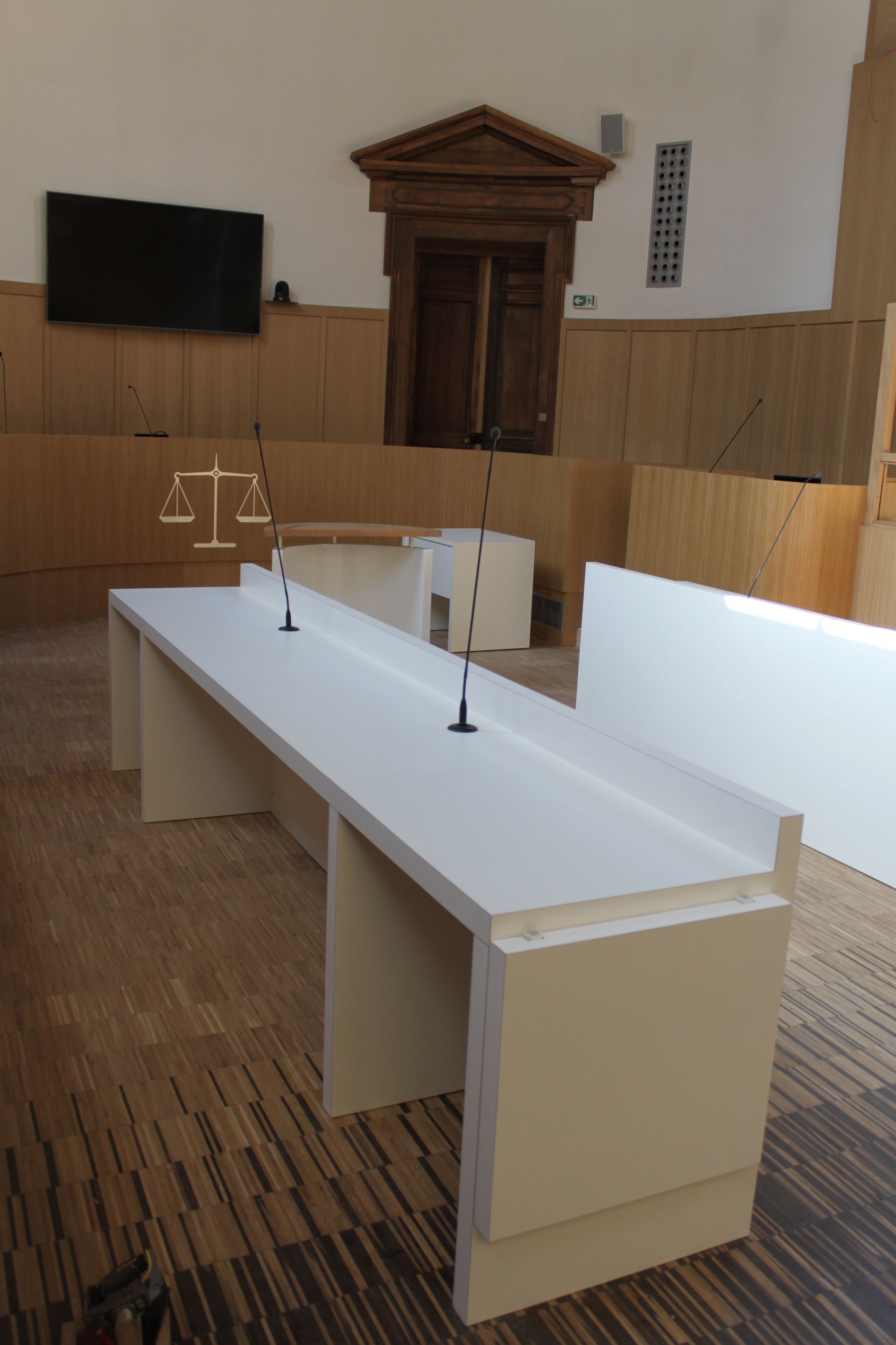 Pupitre blanc avec deux micros dans une salle de tribunal.